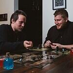 two men sitting at a table playing a board game