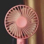 A pink fan sitting on top of a table